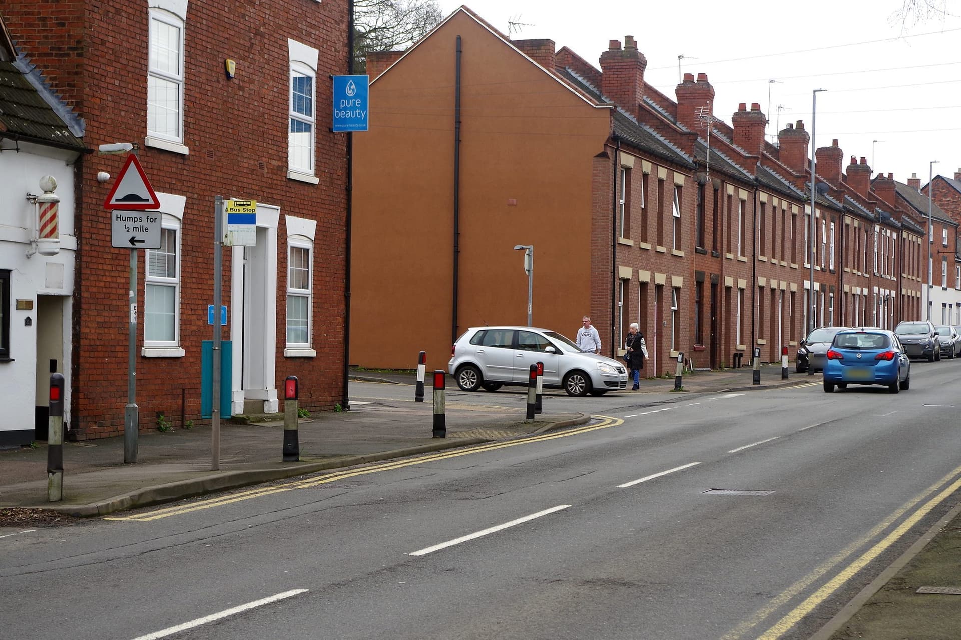 Row of red brick terraced houses with slate roofs and tall brick chimneys on Upper St John Street, Lichfield
