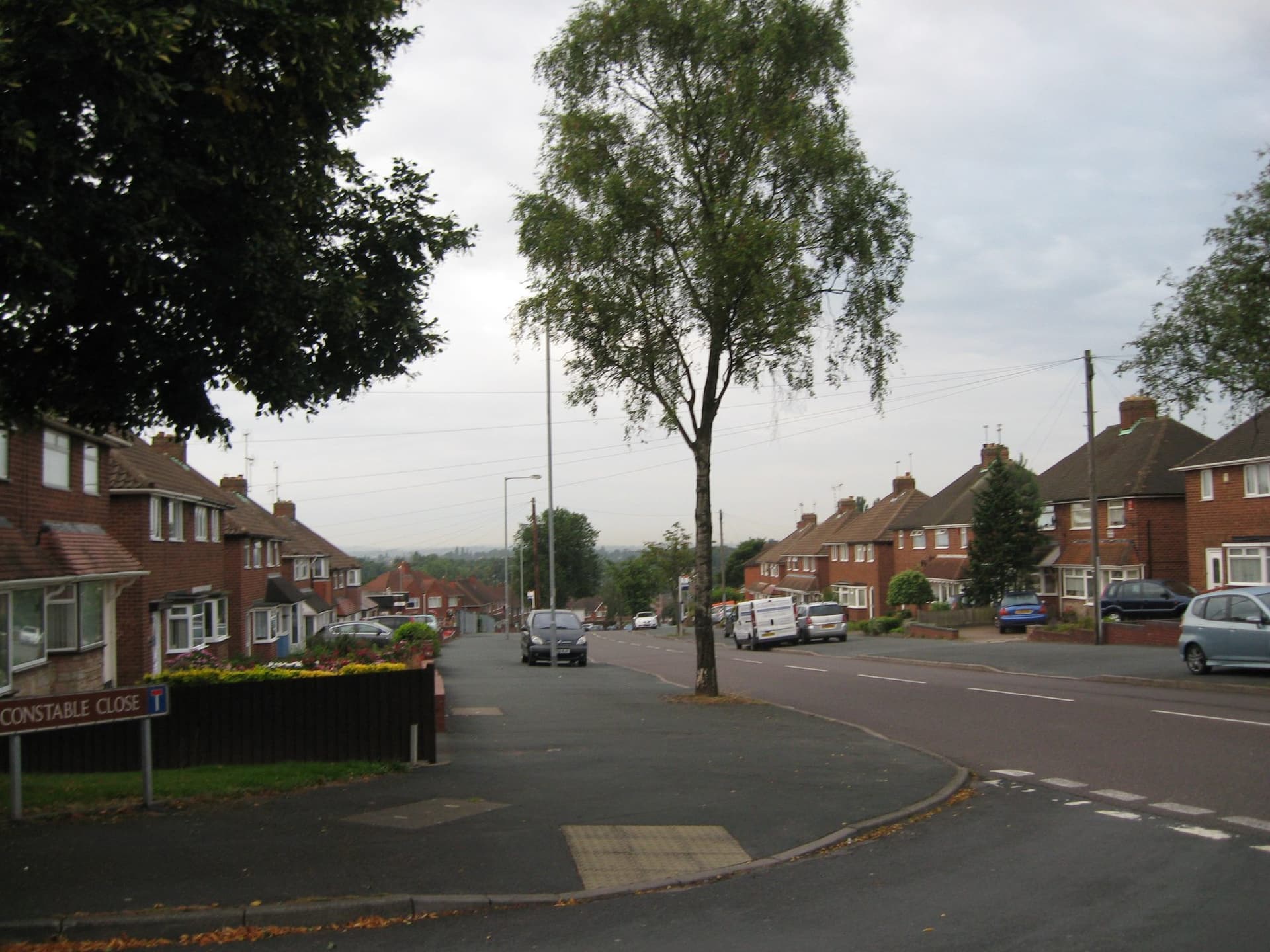 Red brick semi-detached houses with hipped tiled roofs stepping down Hillingford Avenue, Pheasey, Walsall