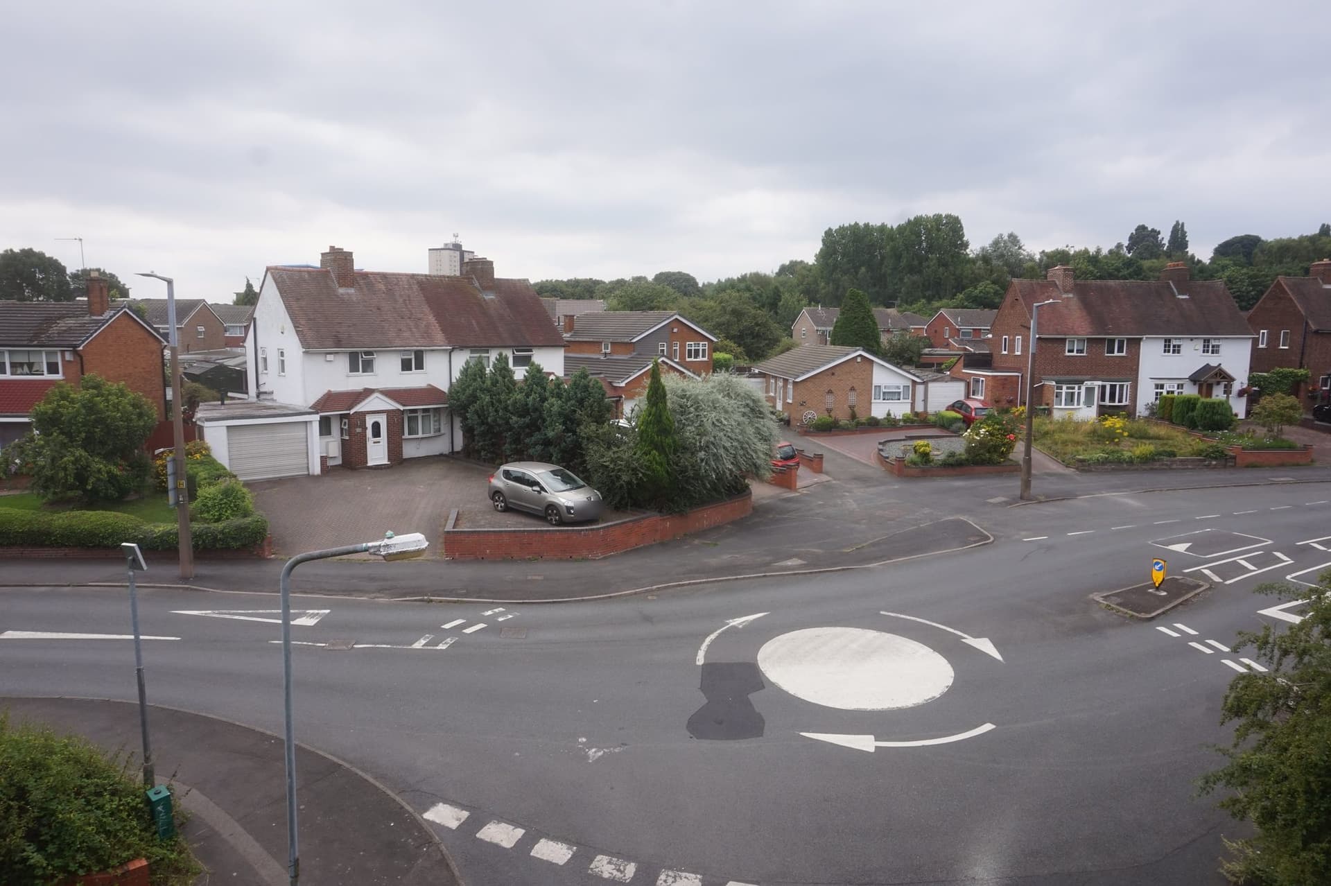 Semi-detached houses, a bungalow and later detached houses with pitched tiled roofs around a mini roundabout on Beaconview Road, West Bromwich