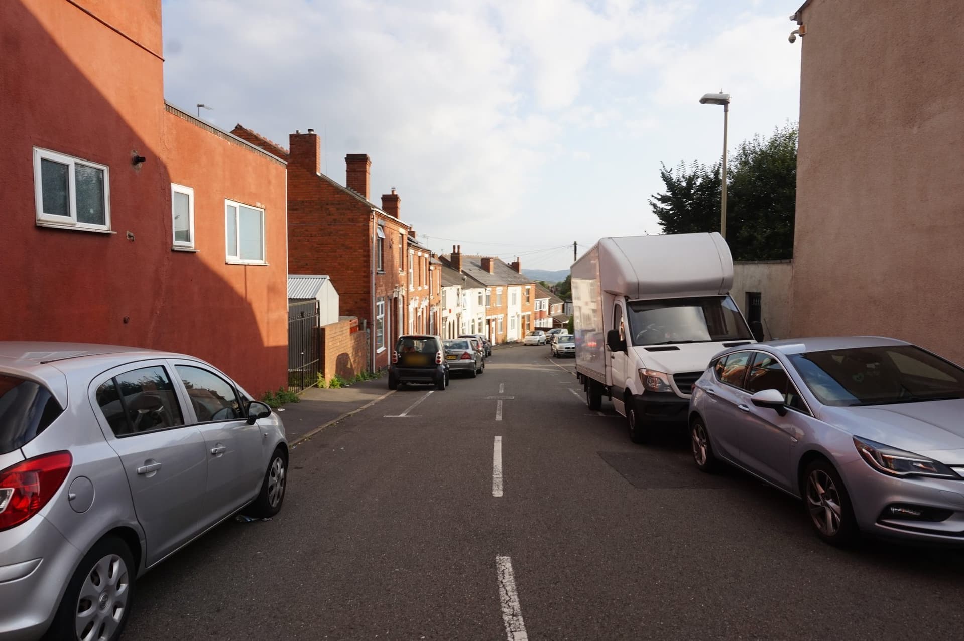 Red-brick and painted terraced houses with slate roofs and chimney stacks on Junction Street, off Queens Cross, Dudley